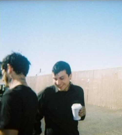 old blurry picture of frank iero laughing with a coffee cup